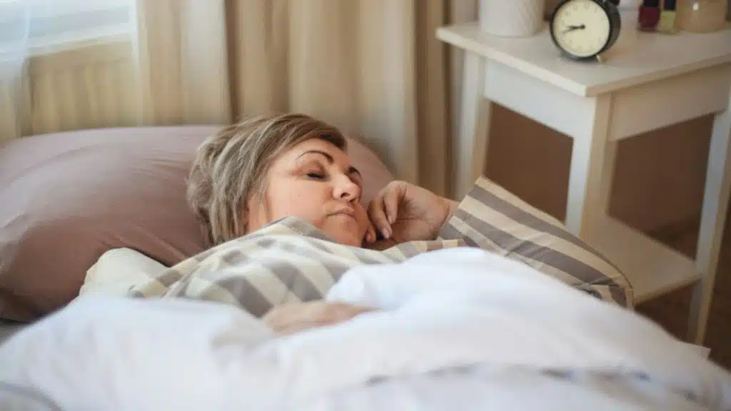 Middle-aged woman with short hair sleeping in a striped pajama top.