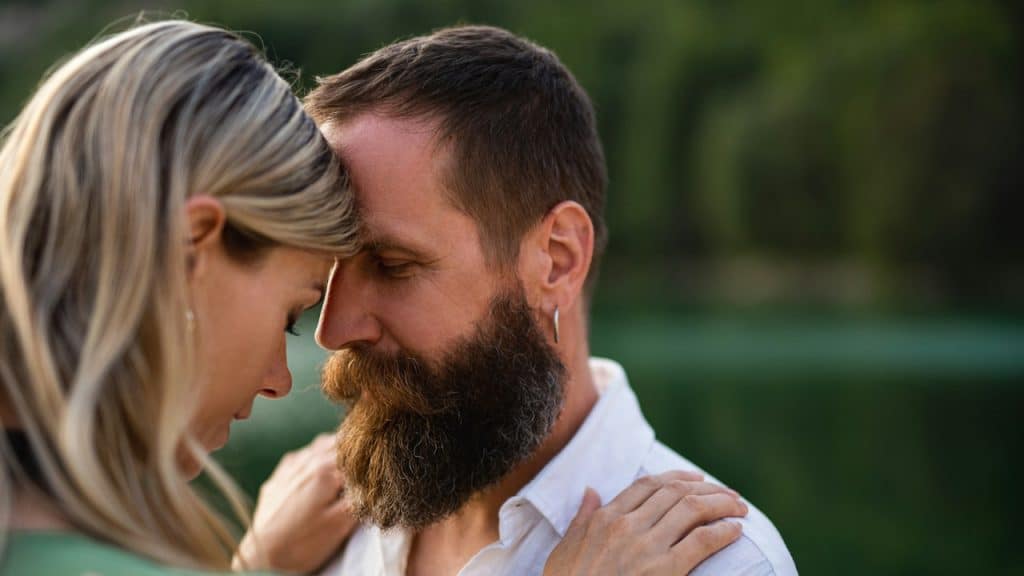 A man and a woman hugging each other in nature.