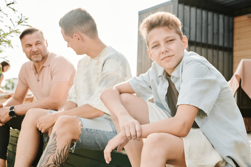 Photograph of a Kid Sitting Near a Man with a Leg Tattoo