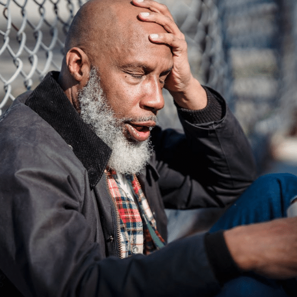 A man sitting on the street holding a beer