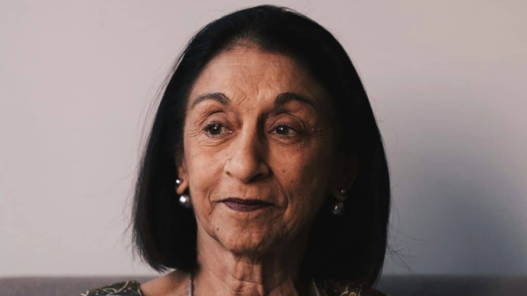 An older woman sitting with a morose expression.