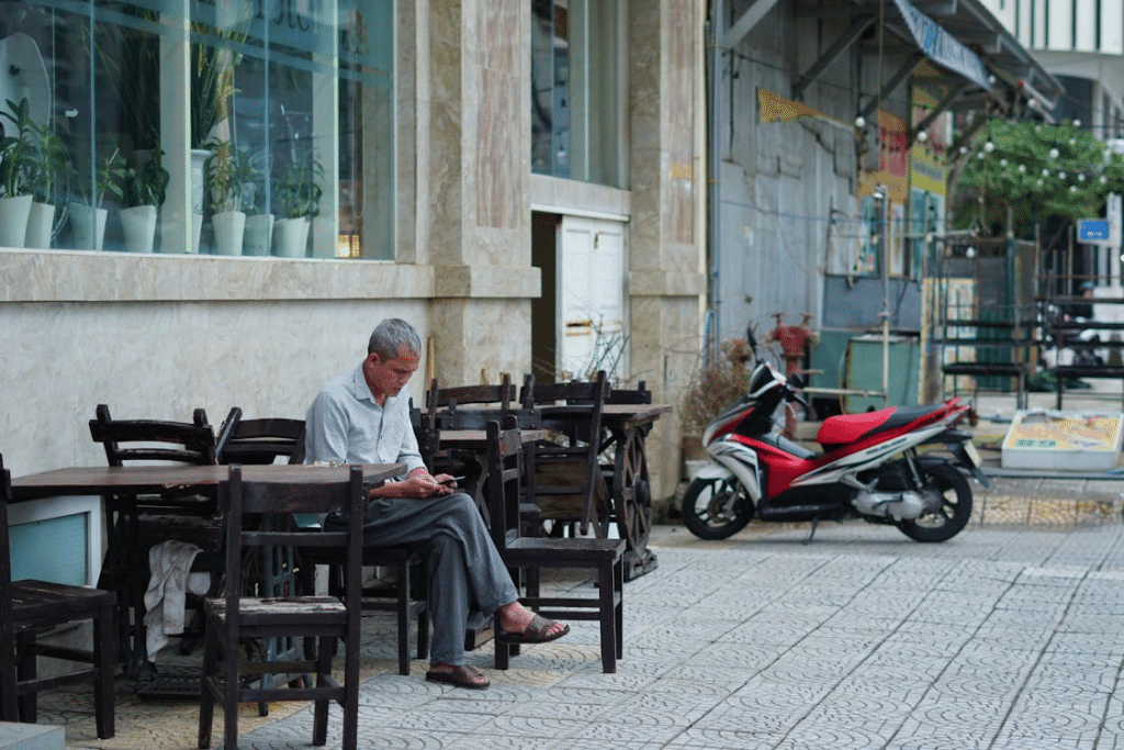 A man using a phone while sitting on a chair outside