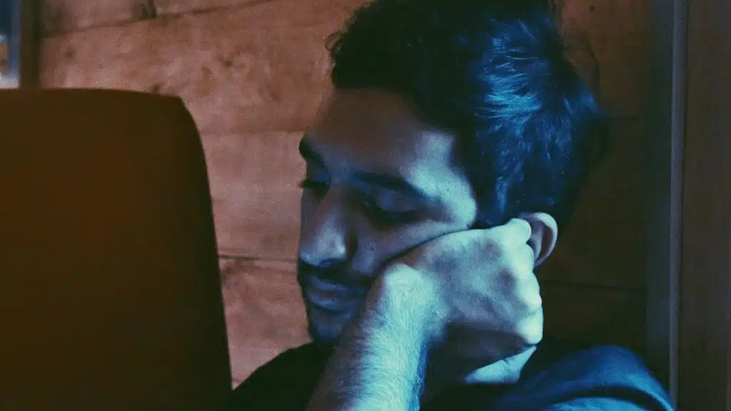 Man leaning his face with a hand and looking at his phone.