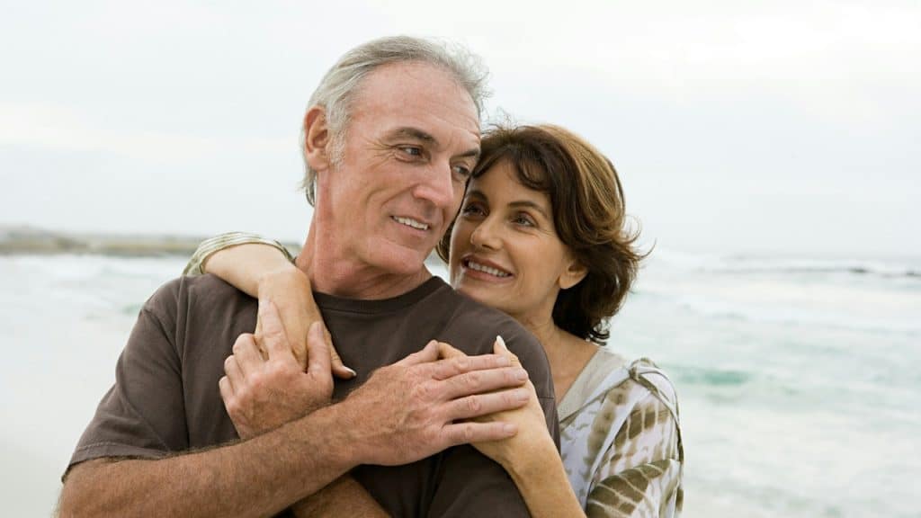 A couple standing on the beach and holding each other.