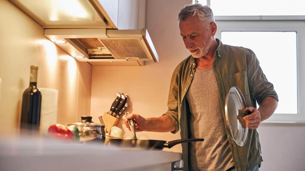 An older man cooking in a kitchen.