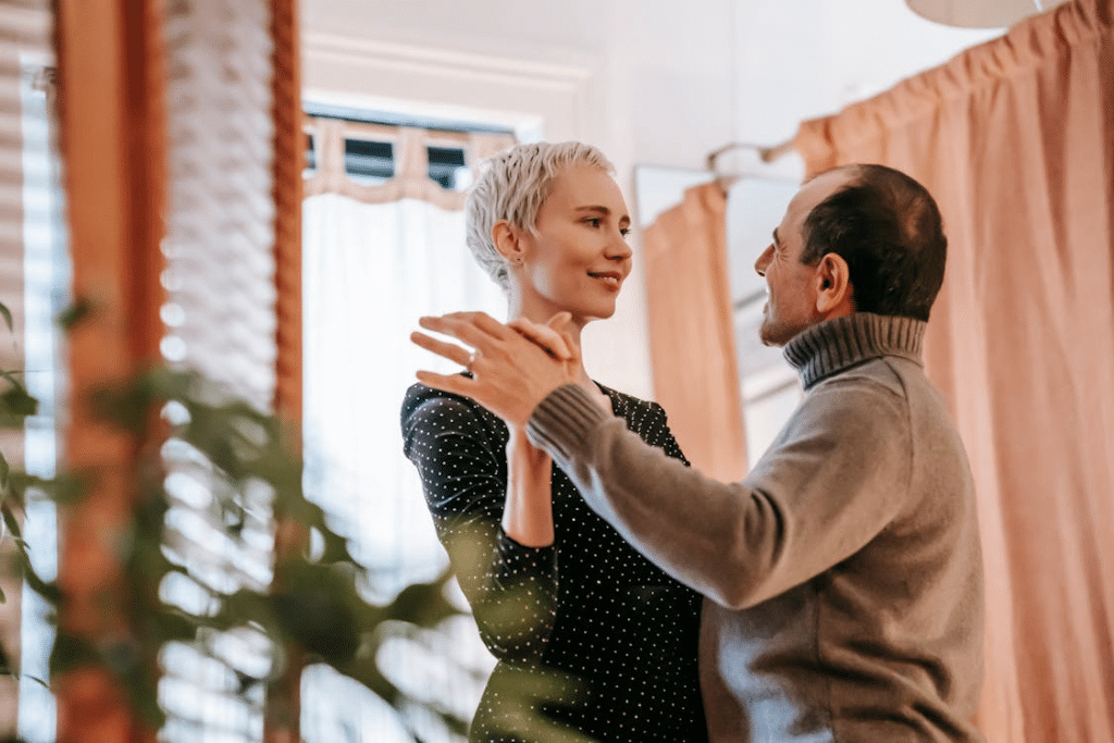 Happy smiling couple dancing together against window