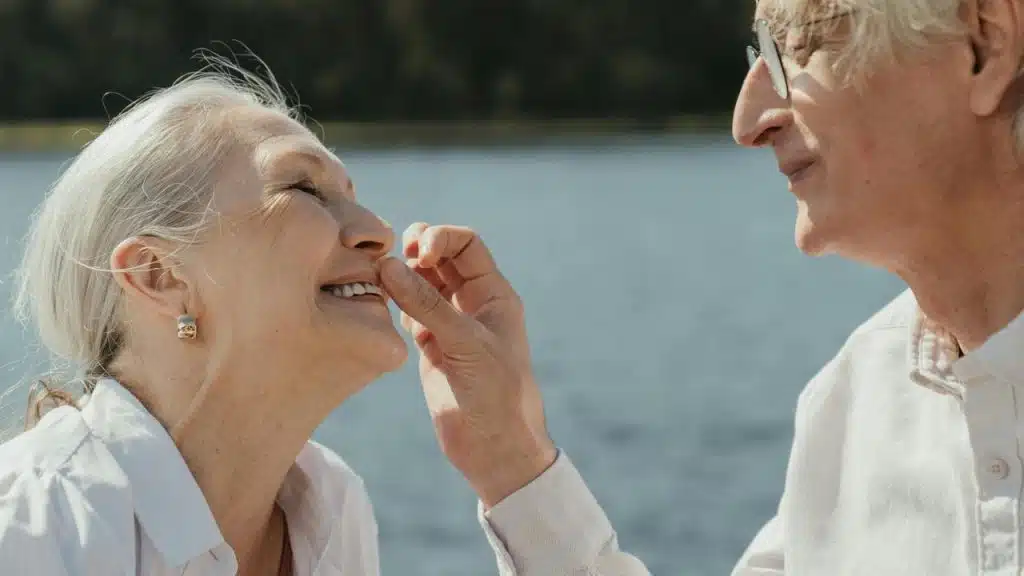 A smiling elderly couple enjoying a tender moment by the water.