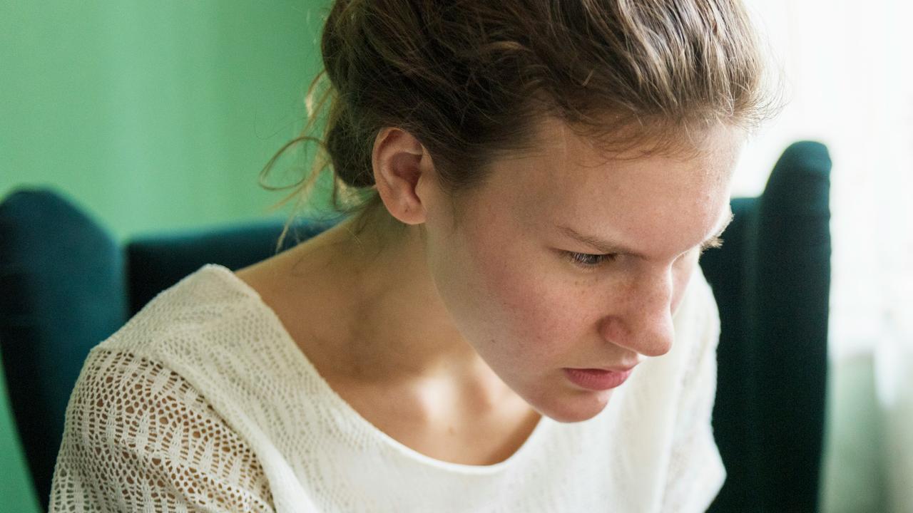 A woman in a white lace top looking focused.