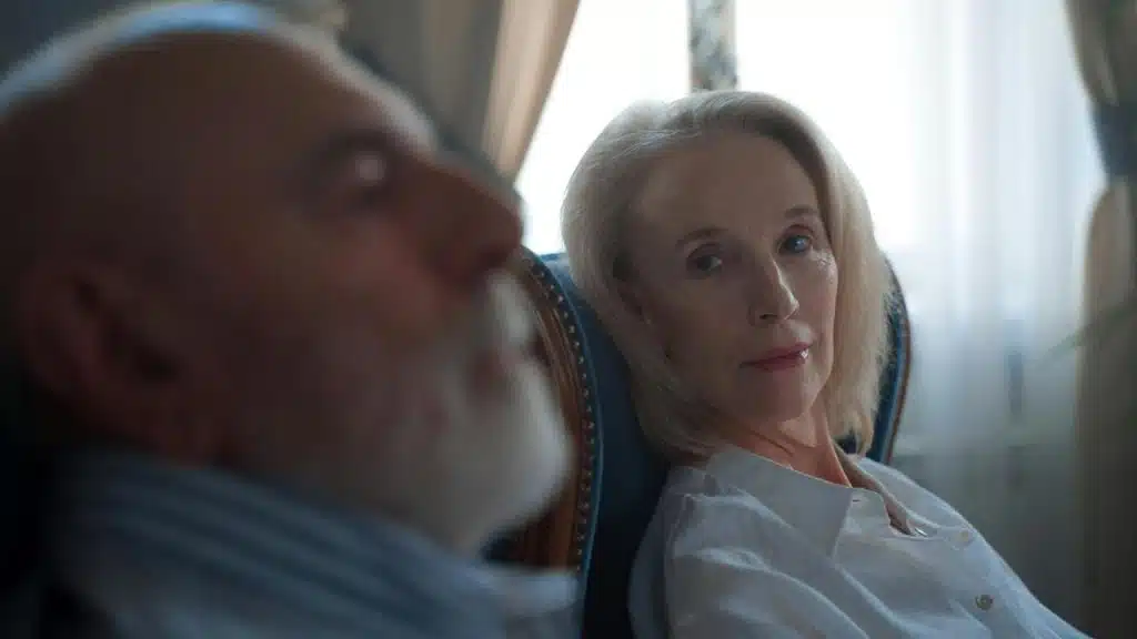 A woman sitting in a chair looking at a man beside her.