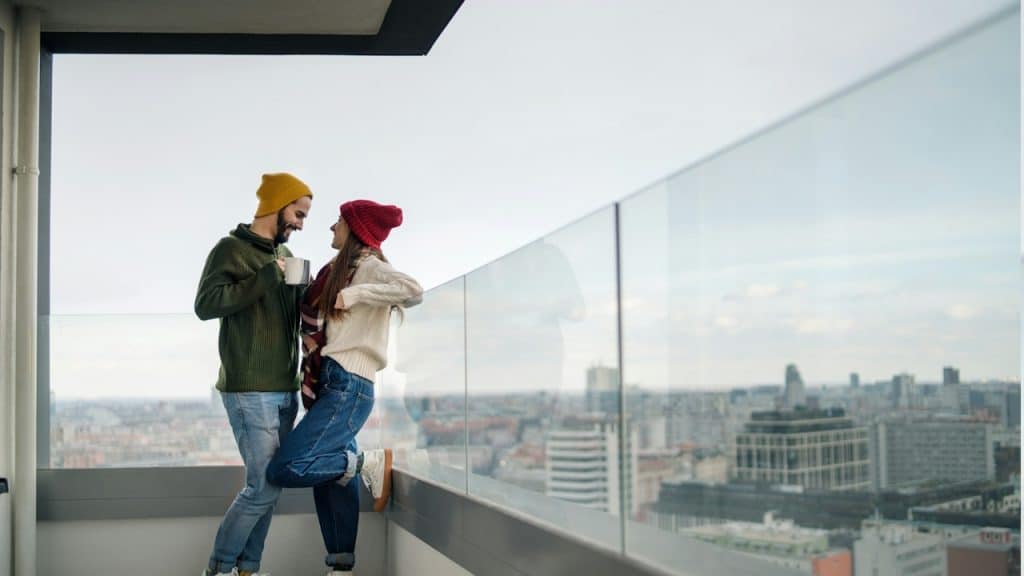A couple standing on the balcony of a new flat.