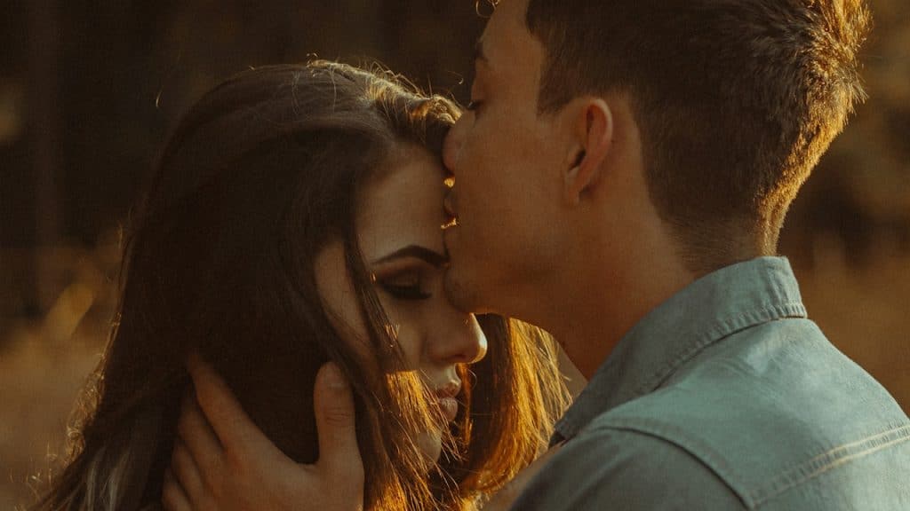 A man kissing a woman’s forehead.
