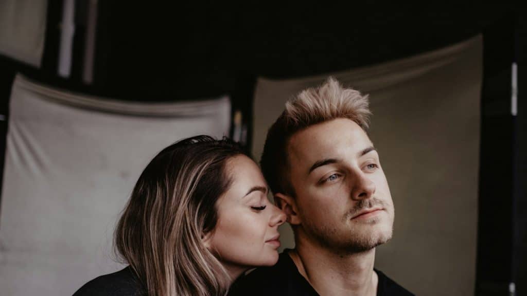 A woman putting her face on the shoulders of a man.