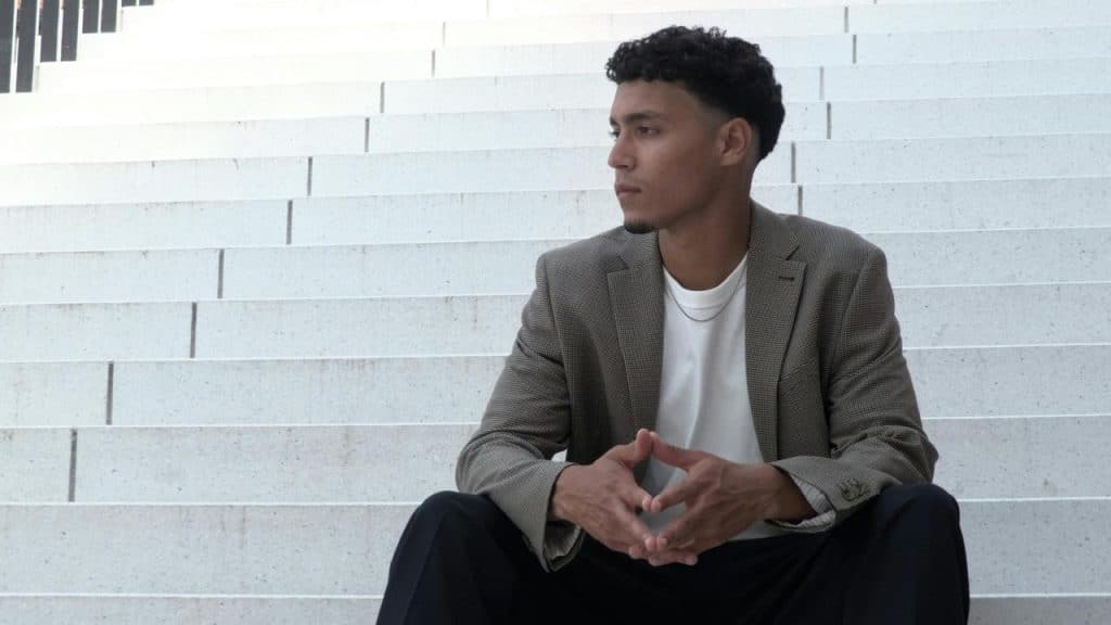 A man sitting on wide white steps looking to the side.