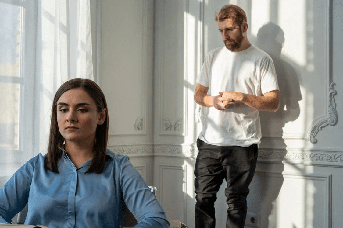 Man in blue polo shirt and black pants standing beside woman in white Long sleeve shirt