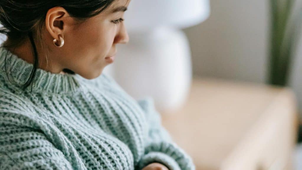A woman in a knitted sweater looking down.