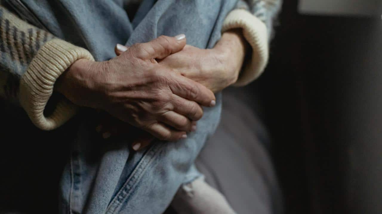 A close-up of someone clasping their hands around their knee.