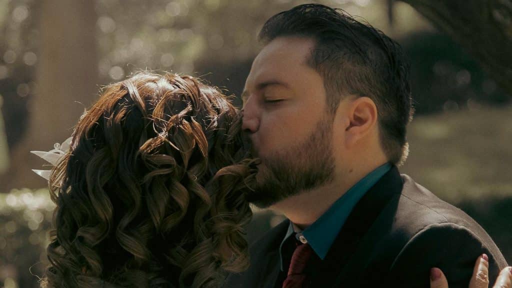 A man kissing a woman’s forehead with his eyes closed.