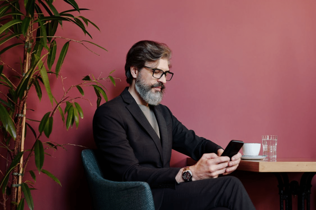 Man Sitting at a Table and Texting