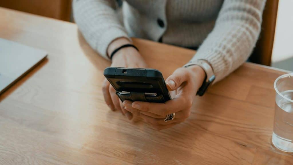 A person sitting at a table holding a smartphone.