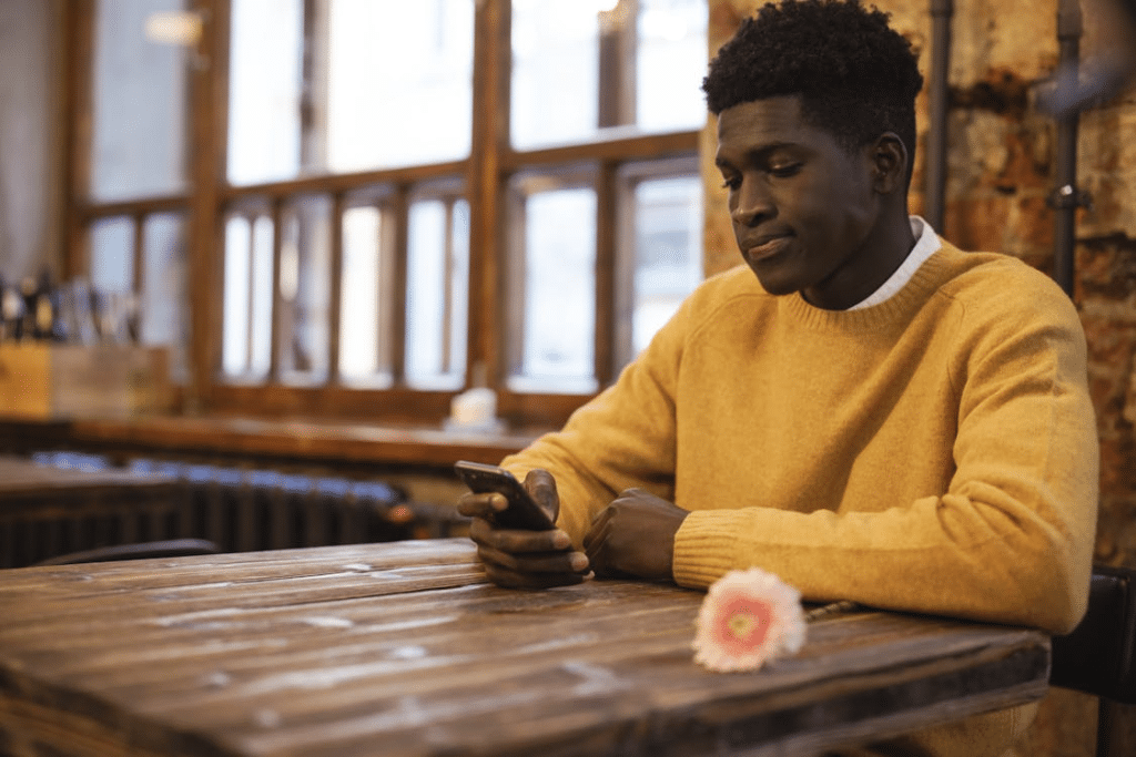 Man in Yellow Sweater using Phone