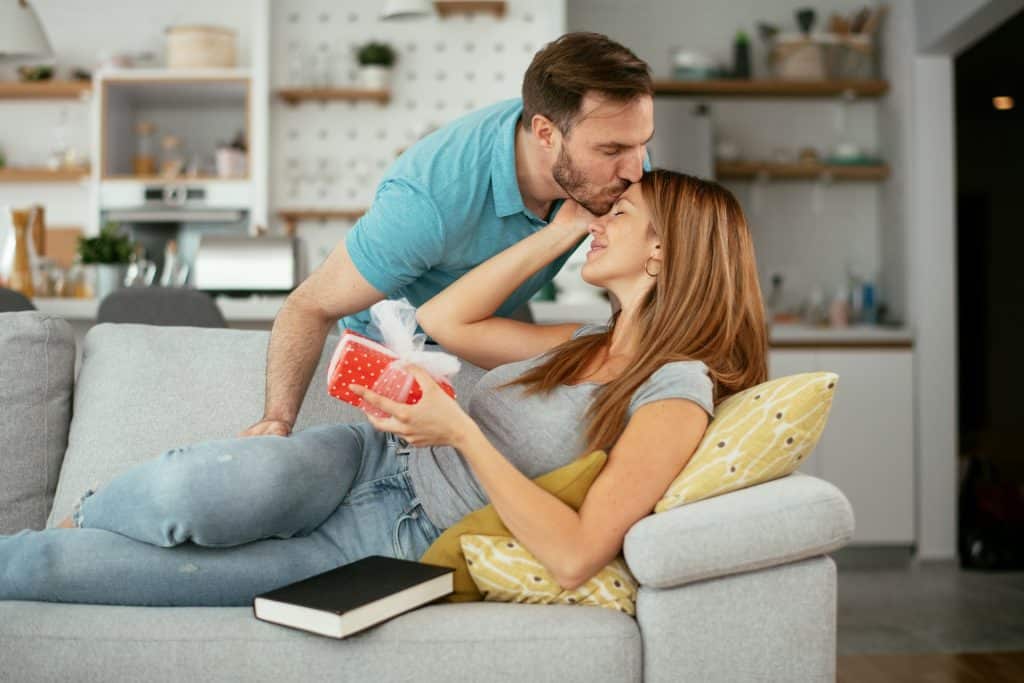 The man kisses the woman as she receives the gift.