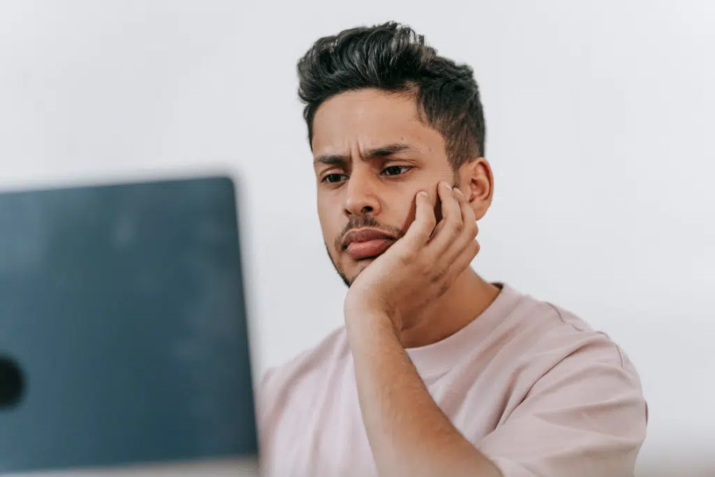 Frowning ethnic man working on laptop