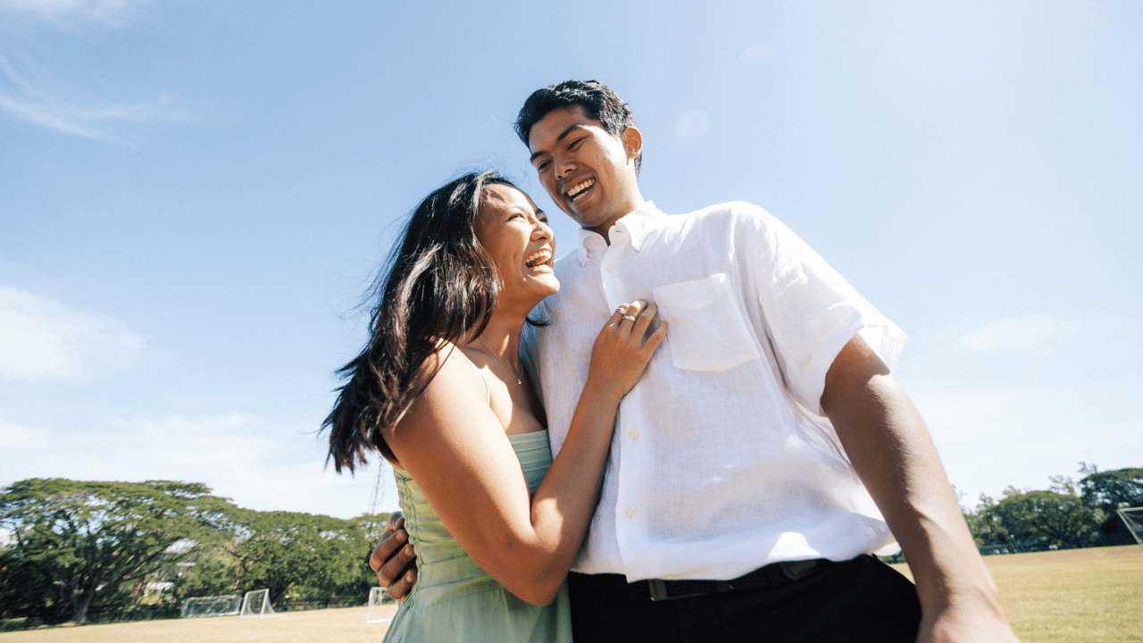 A couple laughing together on a field 