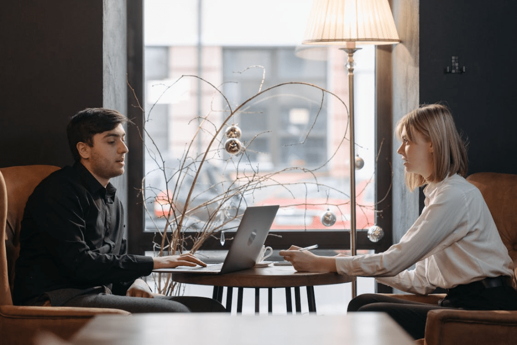 A woman sitting across from a man using a laptop