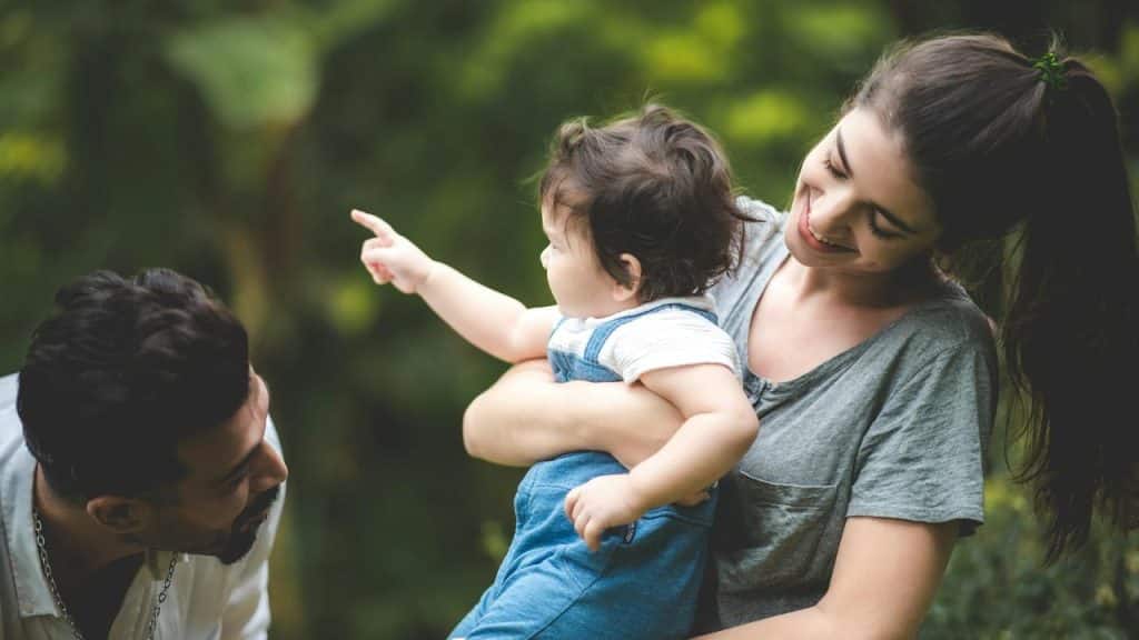 A couple having a good time with their baby outdoors.