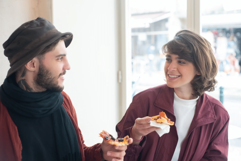 A man and a woman holding slices of pizza