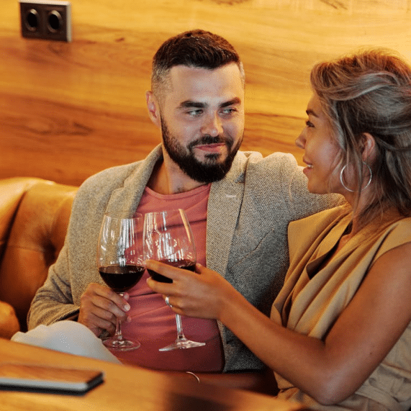A couple sitting and holding glasses of wine