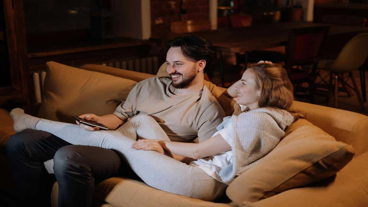 A couple smiling while watching TV