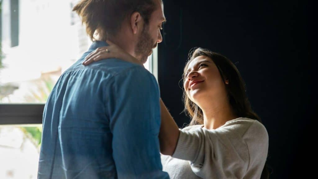 Woman in a white top looking up and smiling at a man in a blue shirt.