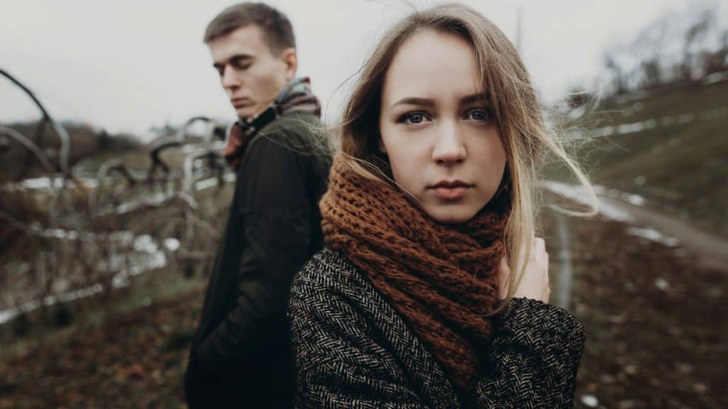A couple standing in a windy autumn park.