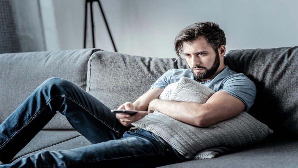 A man looking upset while watching TV