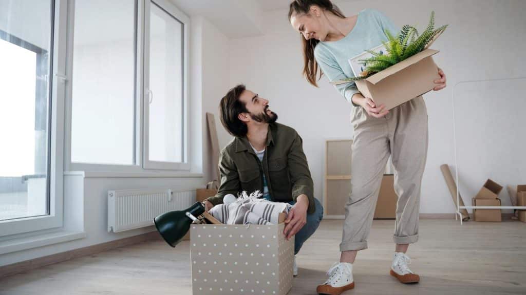 A couple smiling while unpacking boxes in a new home.