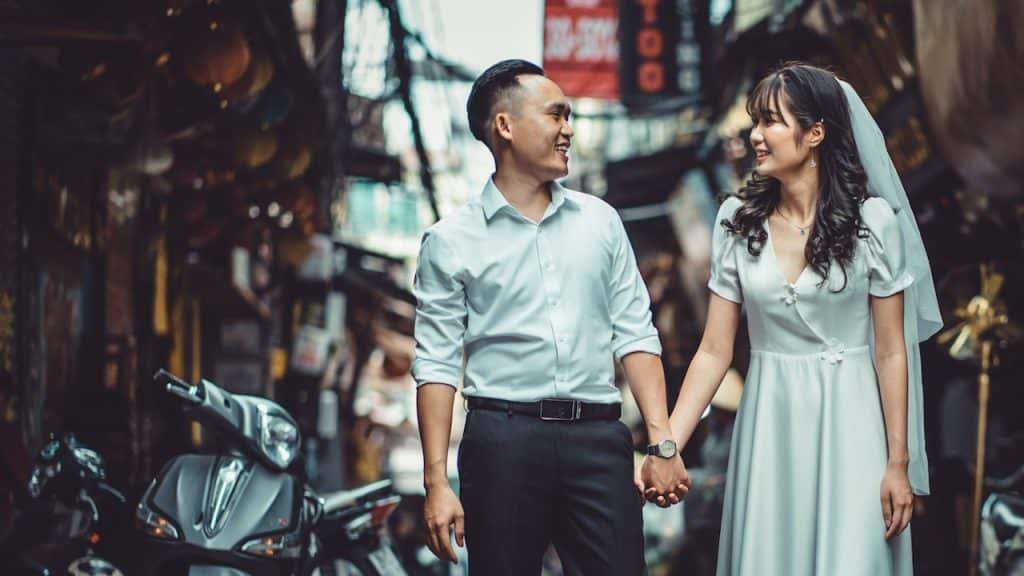 A man and woman holding hands of each other walking down a street.