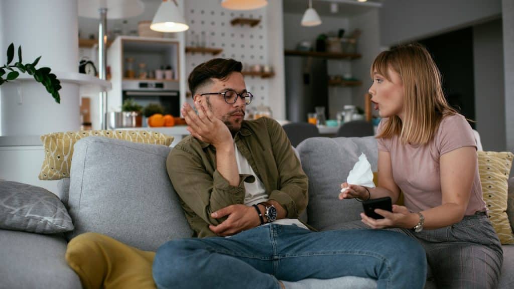 A man and a woman arguing while sitting on a couch.