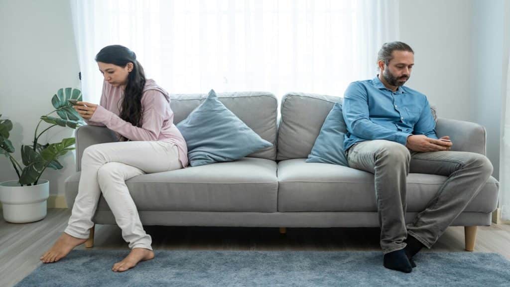 A couple ignoring each other in the living room