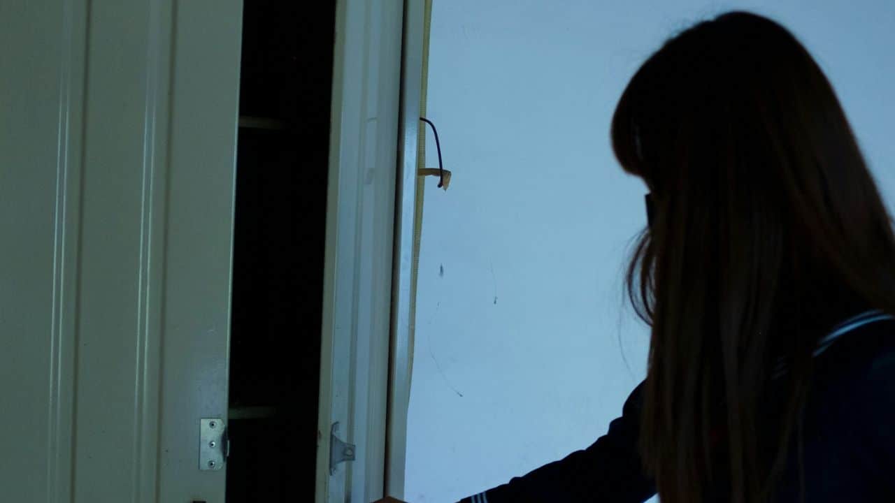 The back of a person's head looking toward a slightly ajar white door.