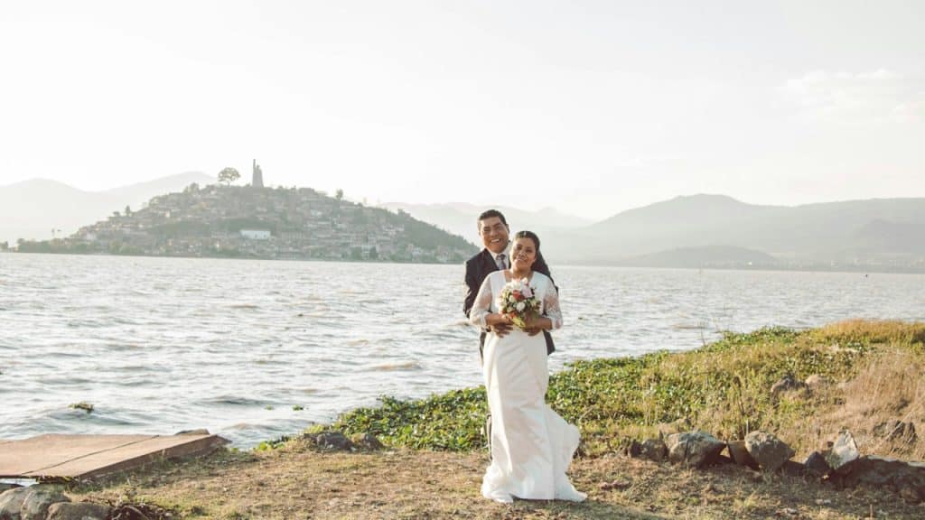 Bride and groom posing in front of a body of water.