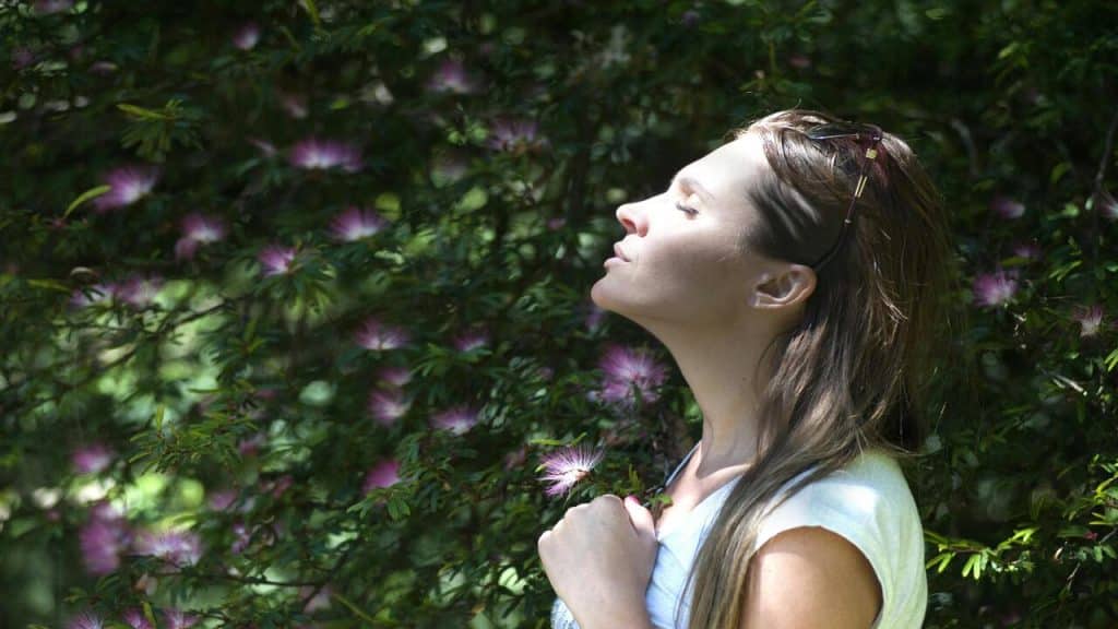 A woman taking a deep breath outside