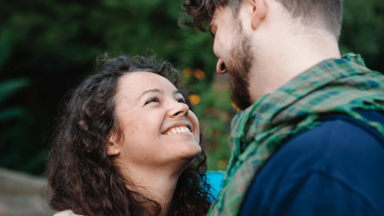 A couple smiling at each other outdoors