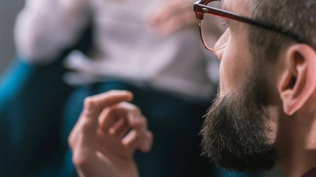 A man wearing glasses listening attentively during a conversation.