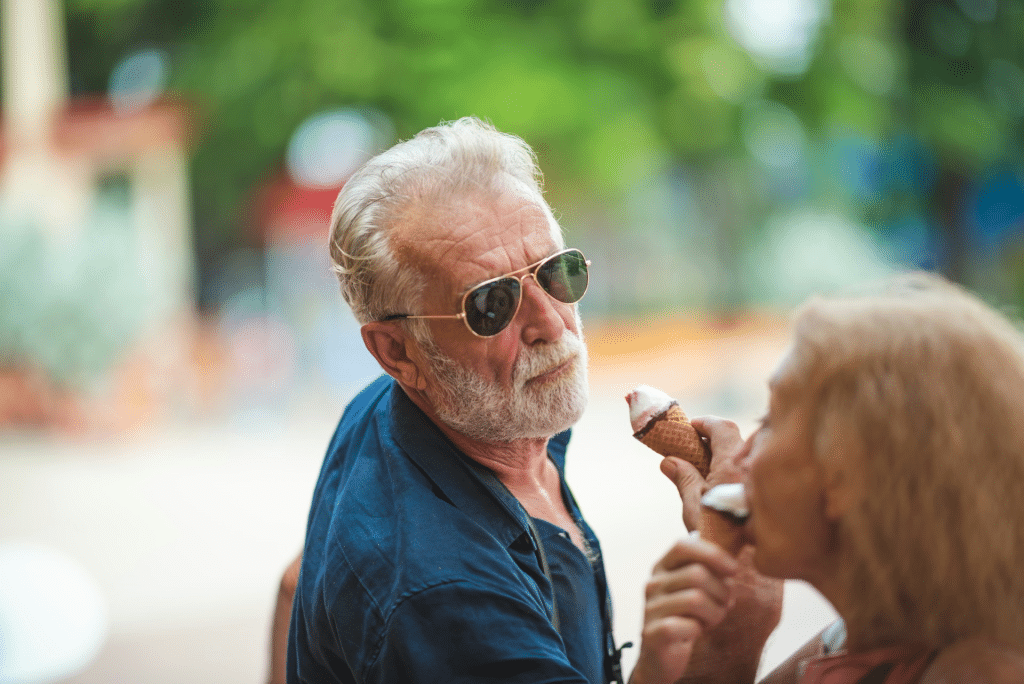 An elderly man eating ice cream with a woman.