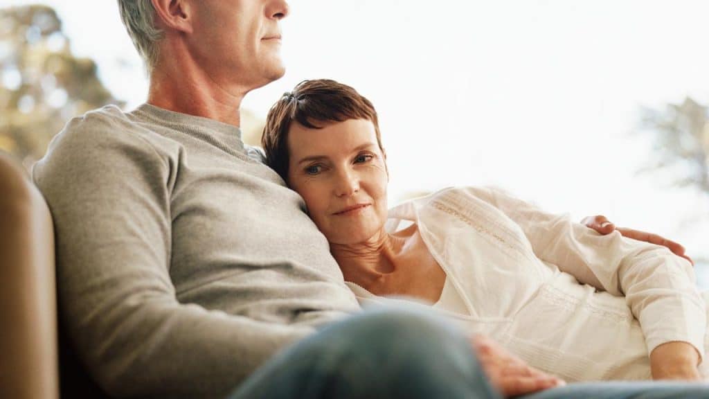 A woman rests her head on a man’s chest as they sit together peacefully.