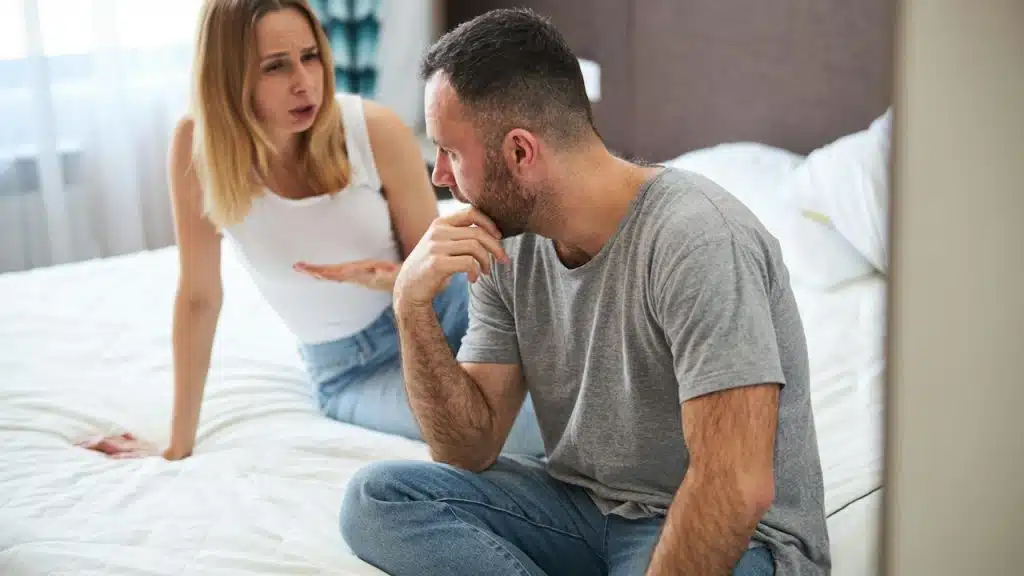 A displeased lady is talking to her husband while her husband touches his chin.