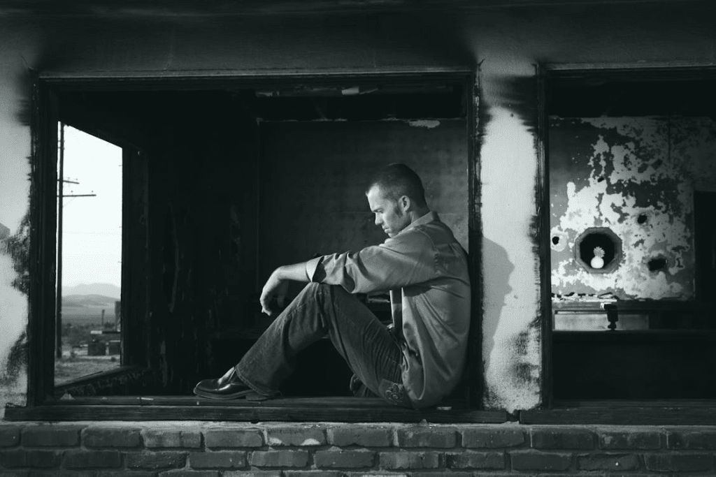 A man sitting and leaning on a column