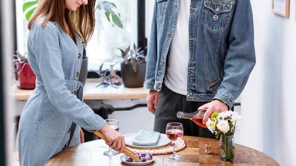 A couple setting the table and pouring drinks together.
