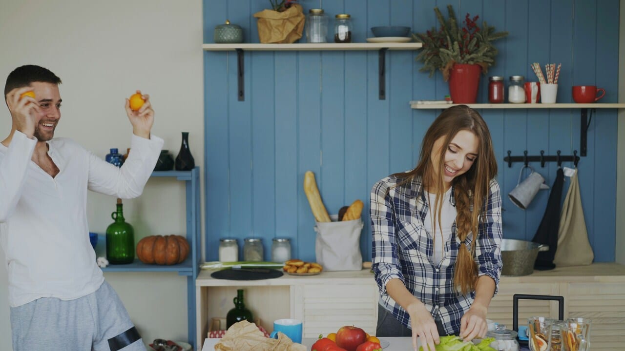 A man cheering on his wife who’s cooking